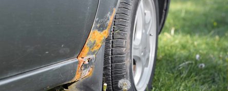 Damage to the car body, corrosion and rust of the front fender from the outside. Holes and metal destruction, selective focus